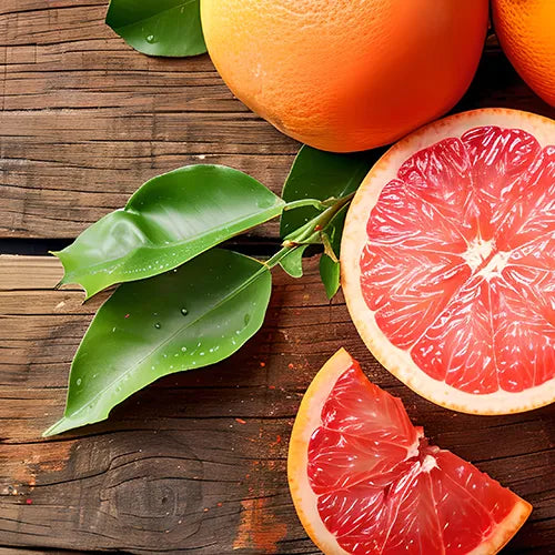 Eine halbierte Grapefruit, ein Grapefruitkeil und ganze Grapefruits mit grünen Blättern sind auf einer rustikalen Holzfläche angeordnet. Das rosarote Fruchtfleisch der Grapefruit ist lebhaft und saftig.