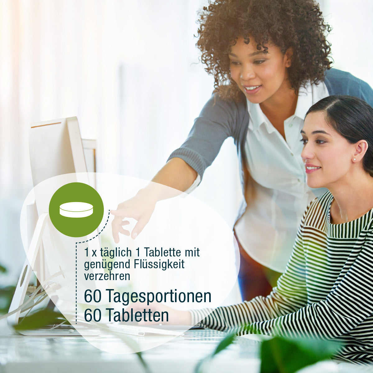 Zwei Frauen arbeiten an einem Computer, eine sitzt und tippt, während die andere auf die deutsche Dosierungsanleitung für Augen Complex (Bio) von gse.organic.supplements zeigt.
