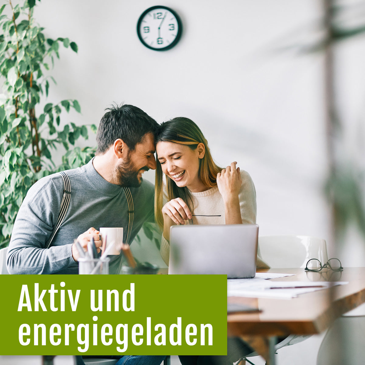 Ein lächelndes Paar sitzt an einem Tisch mit einem Laptop und Kaffeetassen und lehnt sich glücklich aneinander. Im Hintergrund sind eine Uhr und eine Pflanze zu sehen. Der Text auf Deutsch lautet: Aktiv und voller Energie – dank des pflanzlichen Vitamin-B-Komplexes (Bio) von gse.organic.supplements, Ihrem hochwertigen Bio-Nahrungsergänzungsmittel.